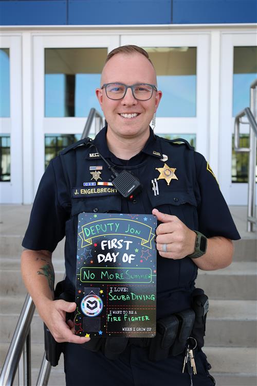 Deputy Jon Engelbrecht holding his first day of school sign.